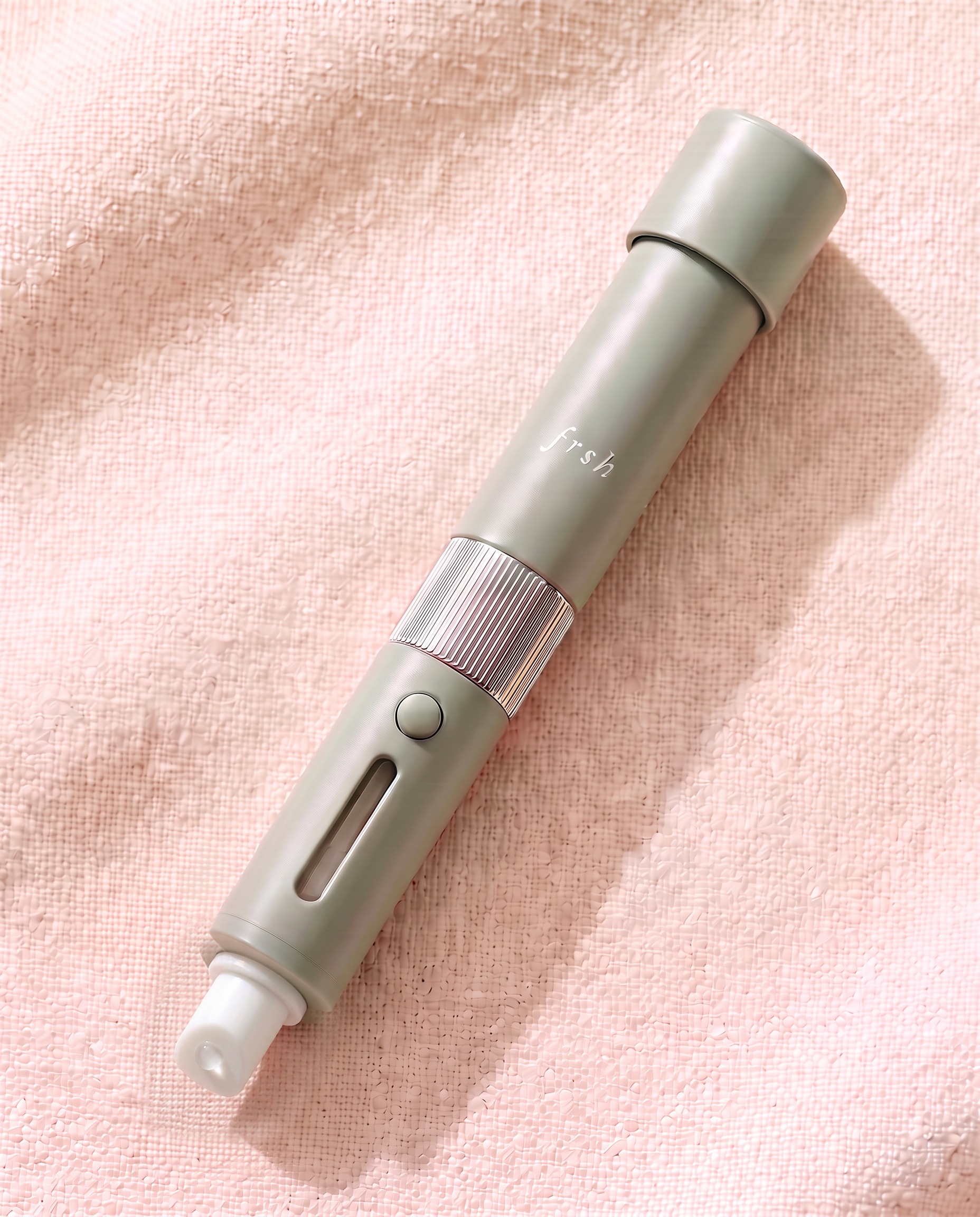 frsh lip balm pod with a slanted applicator dispensing a petroleum-jelly-like balm and its cap parked on the spray sleeve